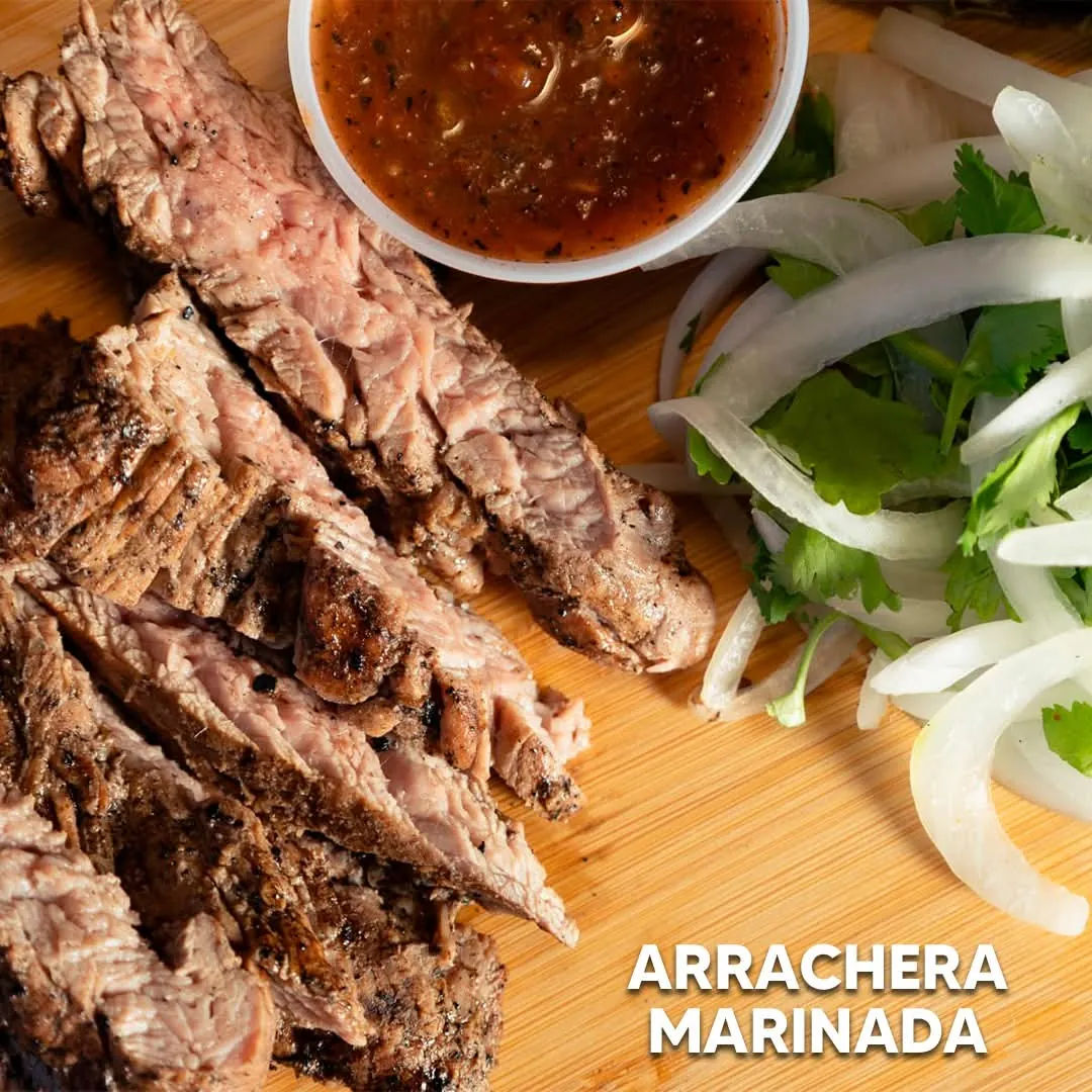 Arrachera marinada rebanada sobre tabla de madera, con salsa, cebolla y cilantro