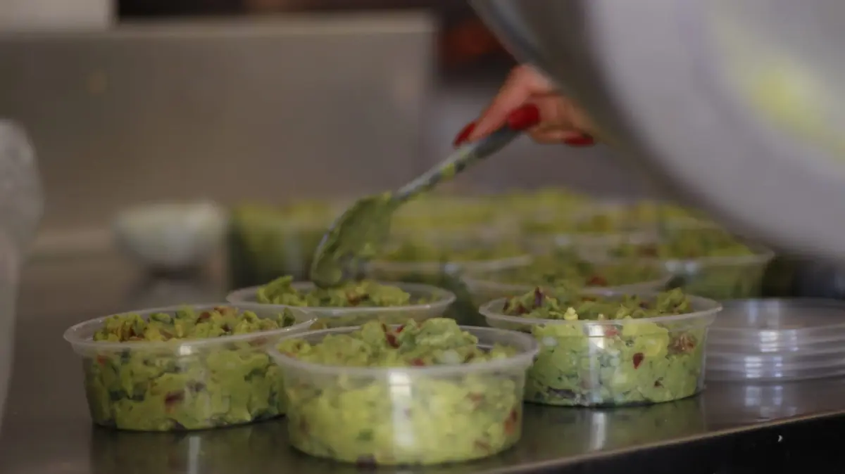 Sirviendo guacamole en vasitos con una pinza
